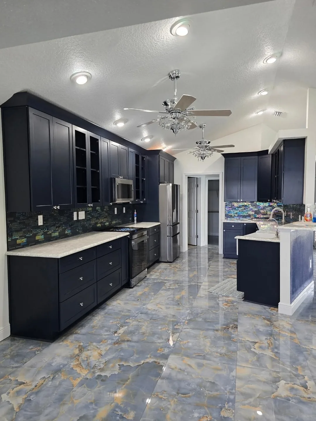 Navy shaker kitchen with iridescent glass mosaic backsplash and blue marble flooring